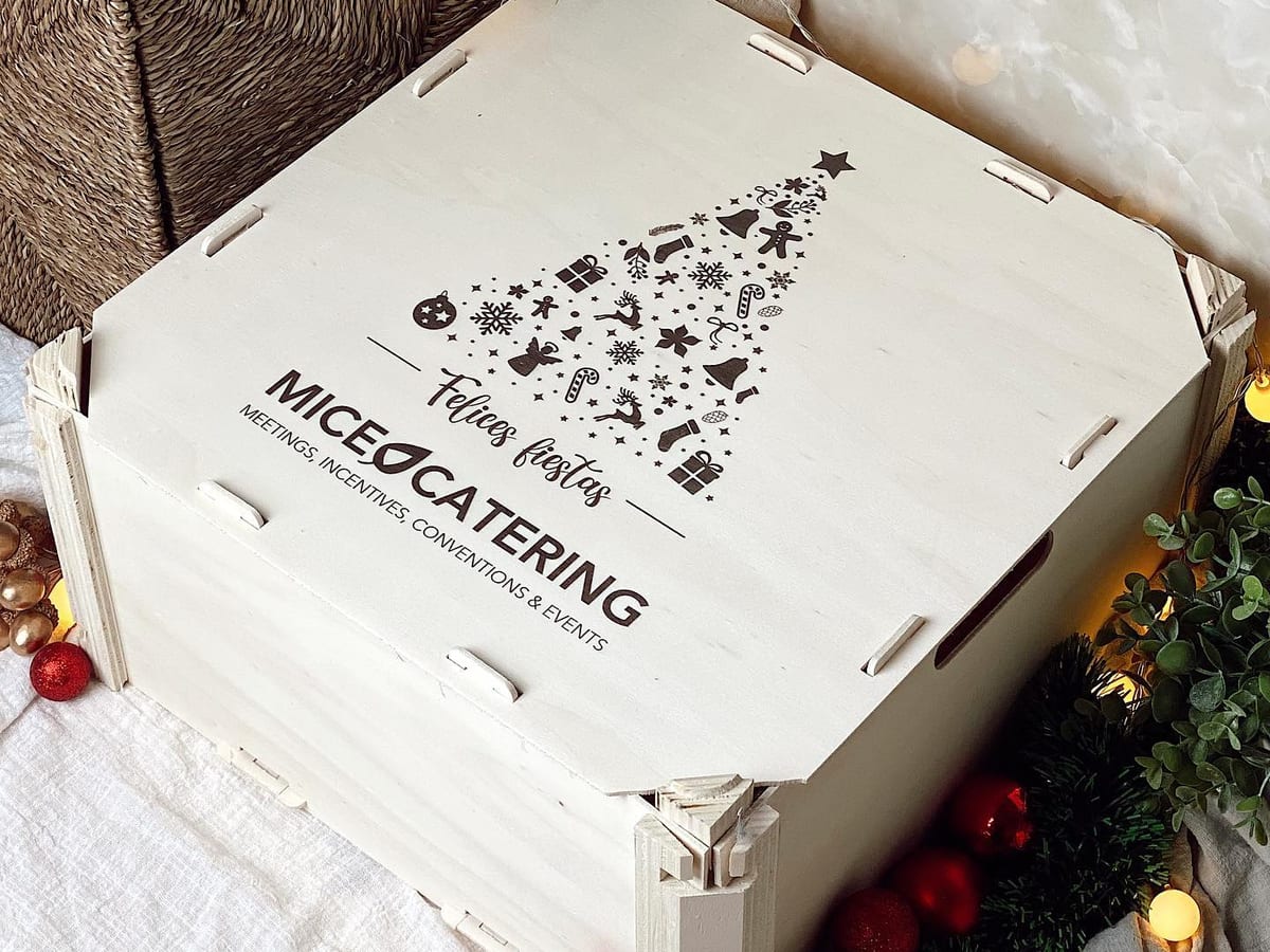Holzkiste mit Deckel, schwarz bedruckt mit dem Logo eines Caterers und einem Weihnachtsbaum, zwischen Weihnachtsdekoration