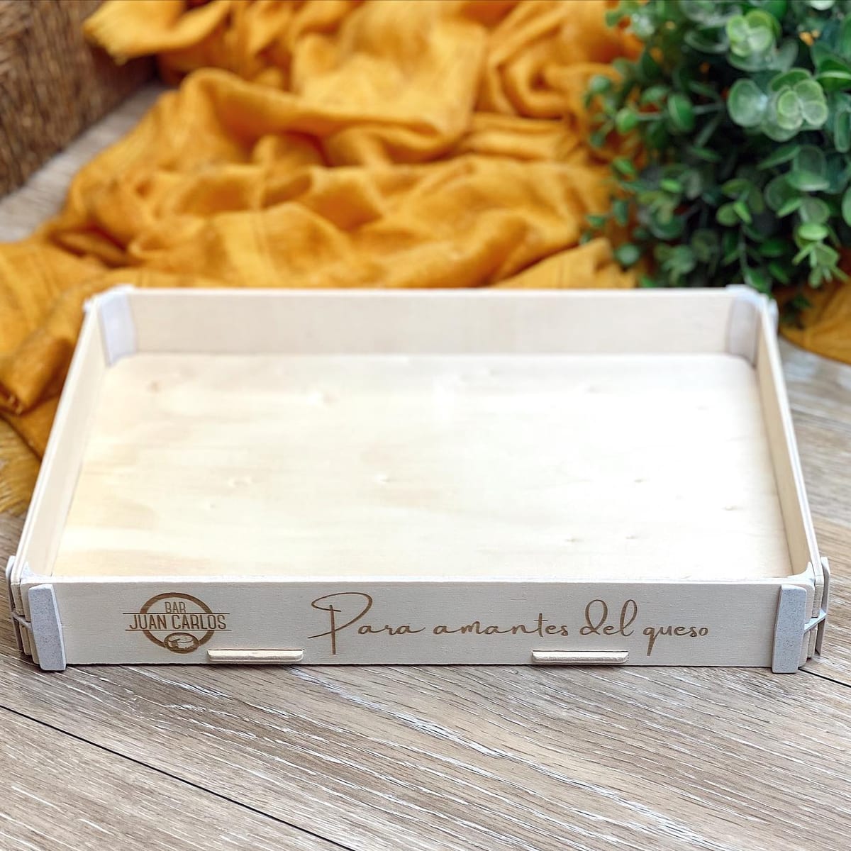 Plateau en bois vide avec le nom d’un bar et « Para amantes del queso » (pour les amoureux du fromage) gravés sur le côté