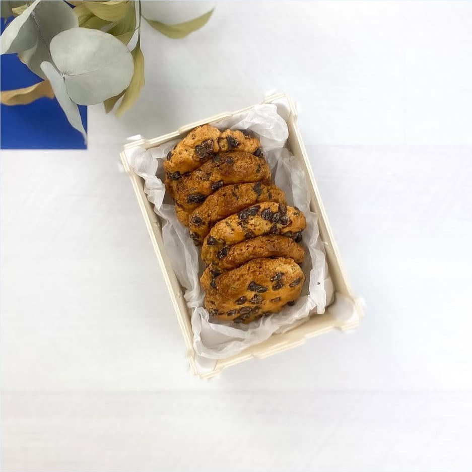 Vista dall’alto di una scatolina di legno senza coperchio con carta velina e biscotti con gocce di cioccolato