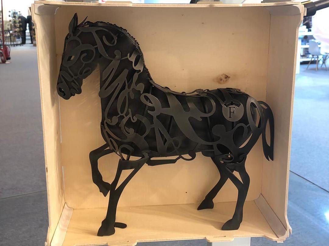 Sculpture en métal d’un cheval debout dans une grande boîte en bois