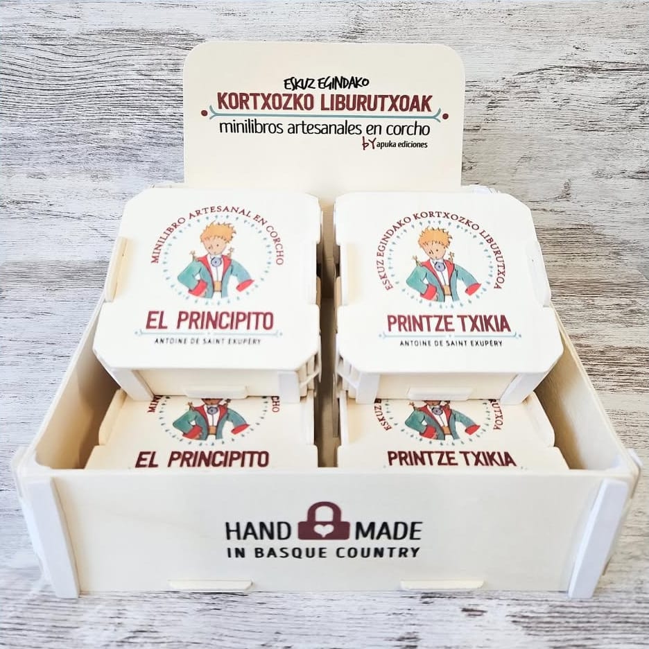 Présentoir en bois Sincla avec un panneau imprimé « minilibros artesanales en corcho » et de petites boîtes à couvercle imprimé pour chaque livre, avec « Hand made in Basque Country » sur la face avant