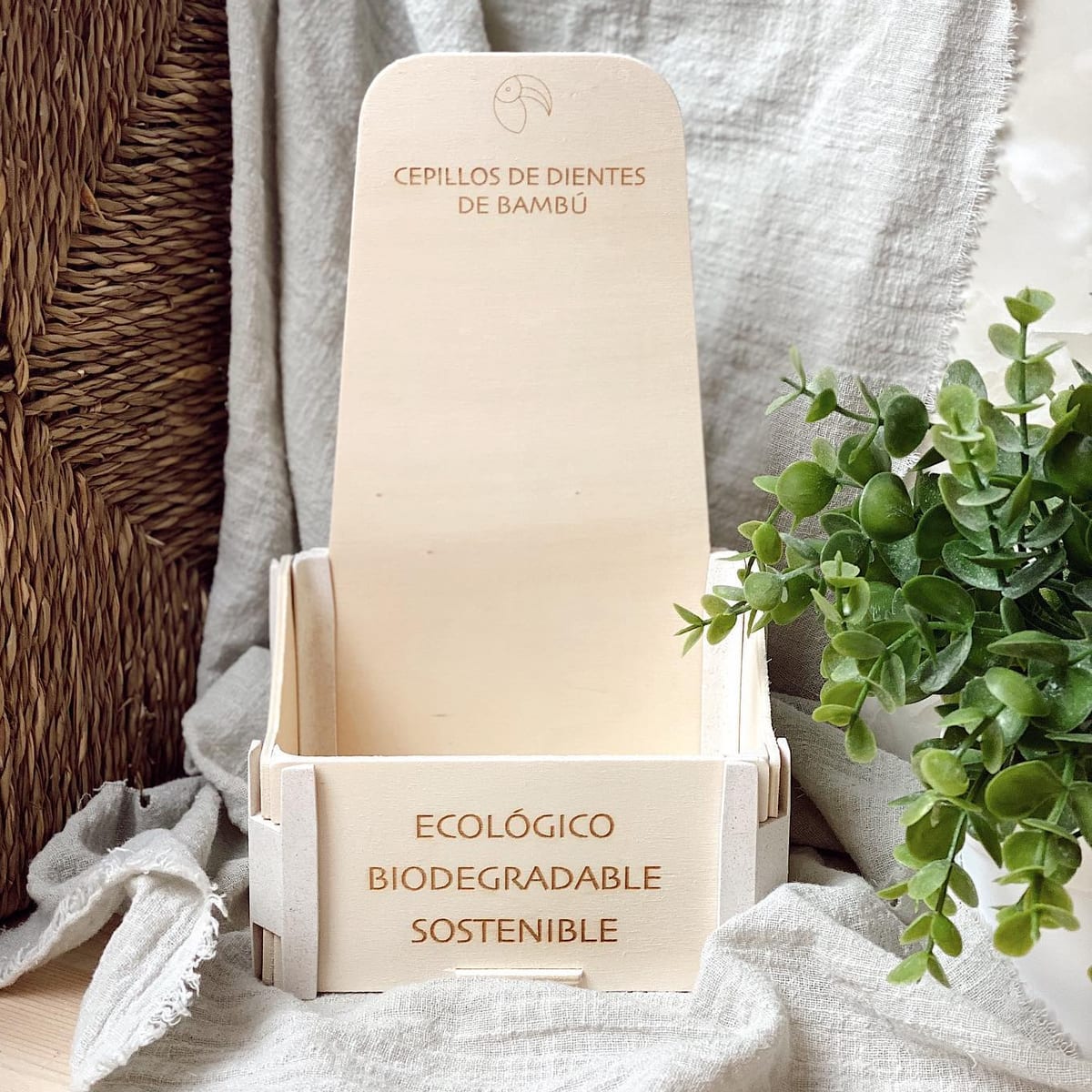 Présentoir de comptoir en bois avec « Ecológico, biodegradable, sostenible » gravé sur la face avant, à côté d’une plante