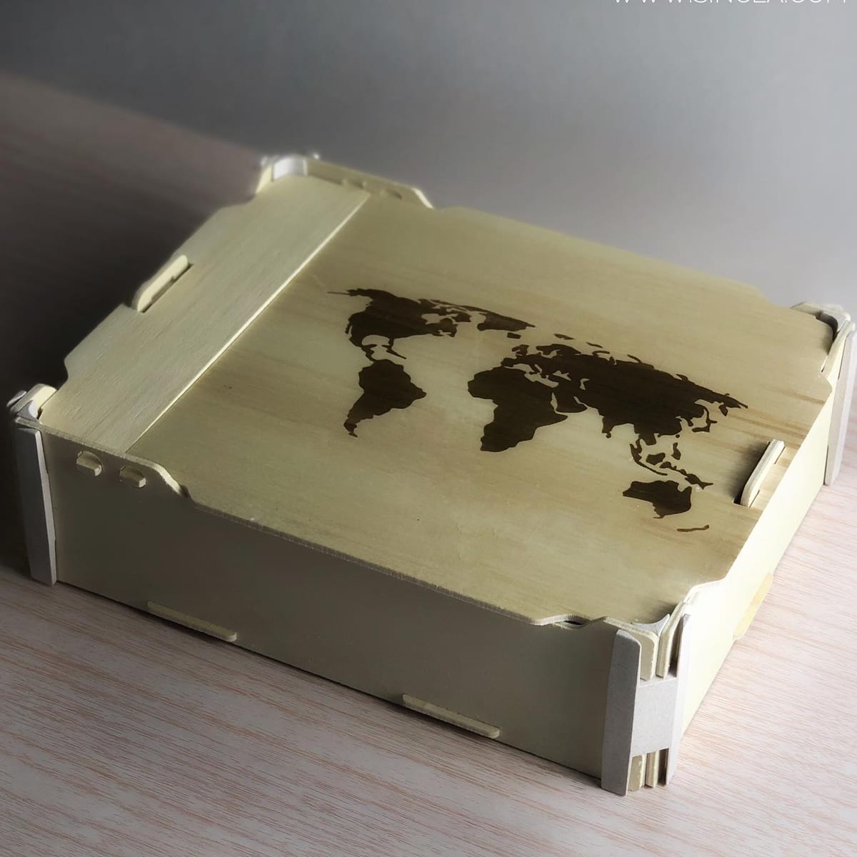 Boîte à charnière avec une carte du monde gravée sur le couvercle, sur une table claire