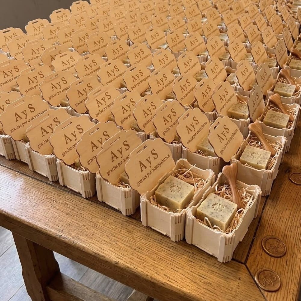 Table en bois couverte de centaines de petites boîtes au couvercle gravé d’initiales, chacune avec une attention pour les invités d’un mariage