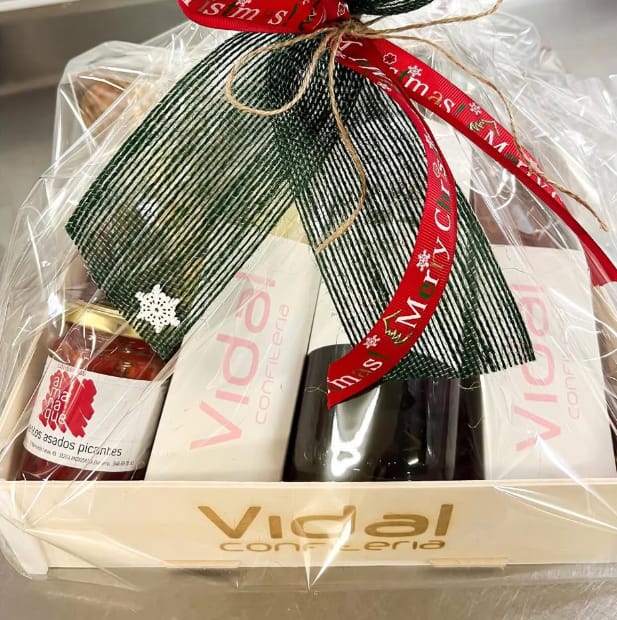 Colis de Noël dans une boîte en bois Sincla gravée « Vidal confitería » sur la face avant, emballé sous cellophane avec un ruban vert et un ruban rouge