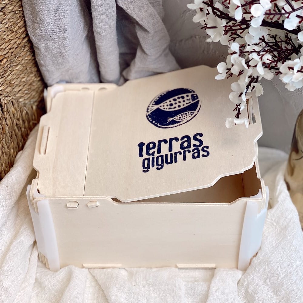 Caja con bisagra de madera con el logo de una marca de aceite impreso en azul en la tapa