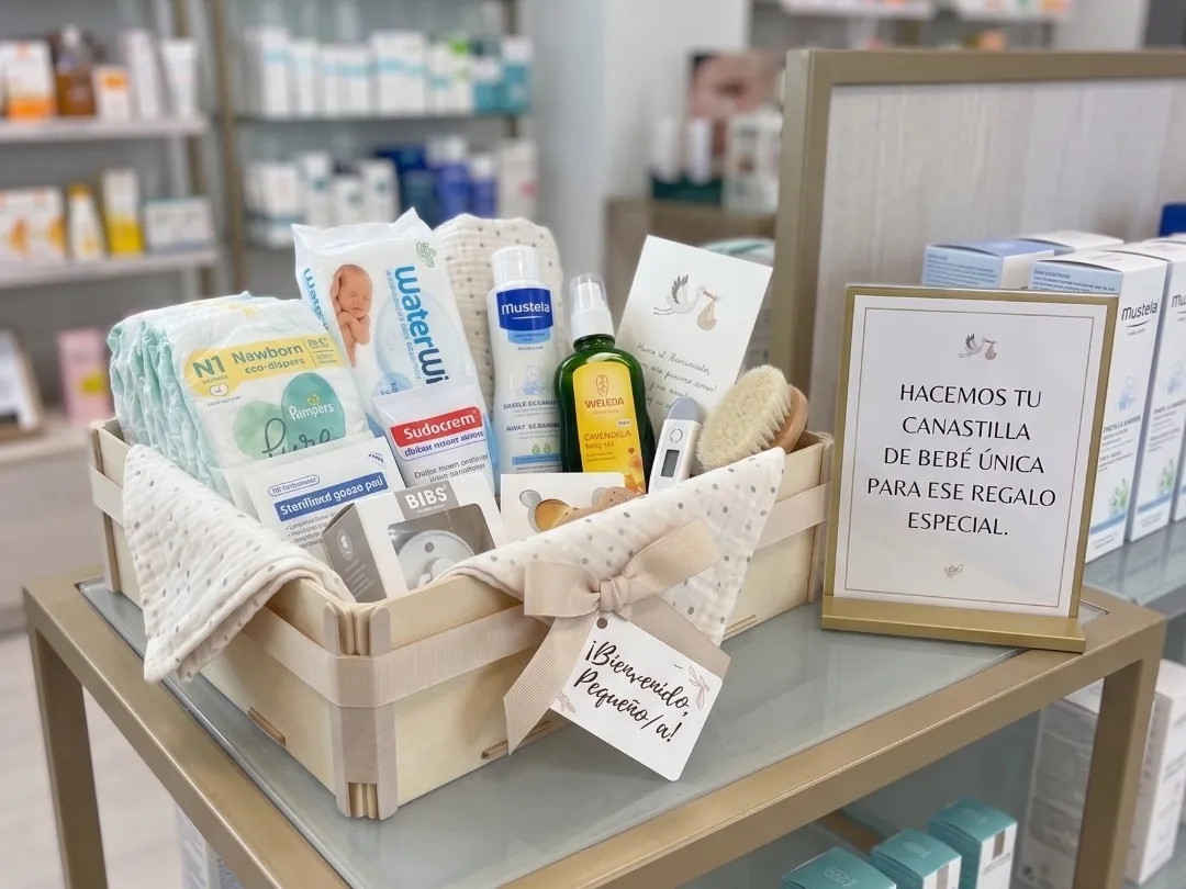 Babyset in einer Holzkiste auf einem Glastisch, daneben ein Schild „Wir stellen Ihr ganz persönliches Babyset zusammen – für dieses besondere Geschenk“