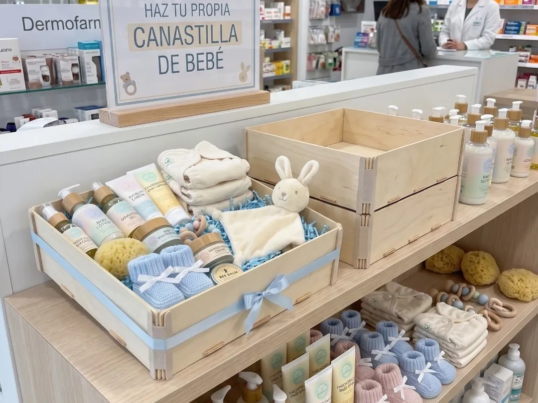 Ecke einer Apotheke mit einem Schild „Stellen Sie Ihr eigenes Babyset zusammen“ und Holzkisten, eine voller Babyprodukte, eine leer