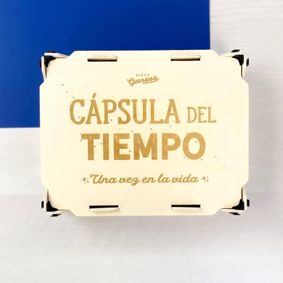 Tampa de madeira com «Cápsula del tiempo – Una vez en la vida» (cápsula do tempo, uma vez na vida) gravado em letras douradas, com cantoneiras pretas