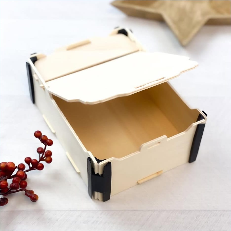 Caja de madera con tapa de bisagra entreabierta y esquineras negras, junto a unas bayas rojas