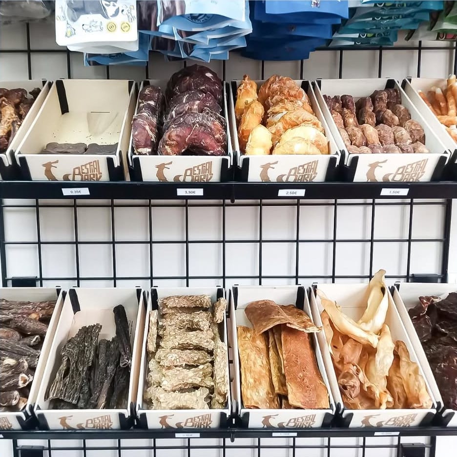 Pared de una tienda con dos filas de cajas de madera sin tapa inclinadas, llenas de snacks y con el logotipo de la tienda grabado