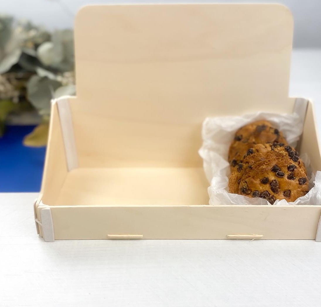 Expositor de madera con la trasera alta y unas galletas en uno de sus huecos, sobre un mostrador blanco