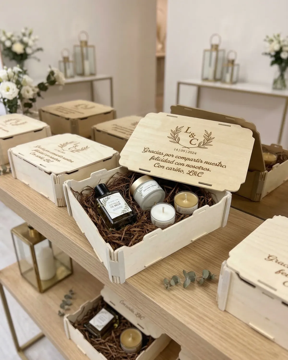 Cajas de madera con las iniciales de los novios y una frase de agradecimiento grabadas en la tapa, con una vela y un perfume dentro