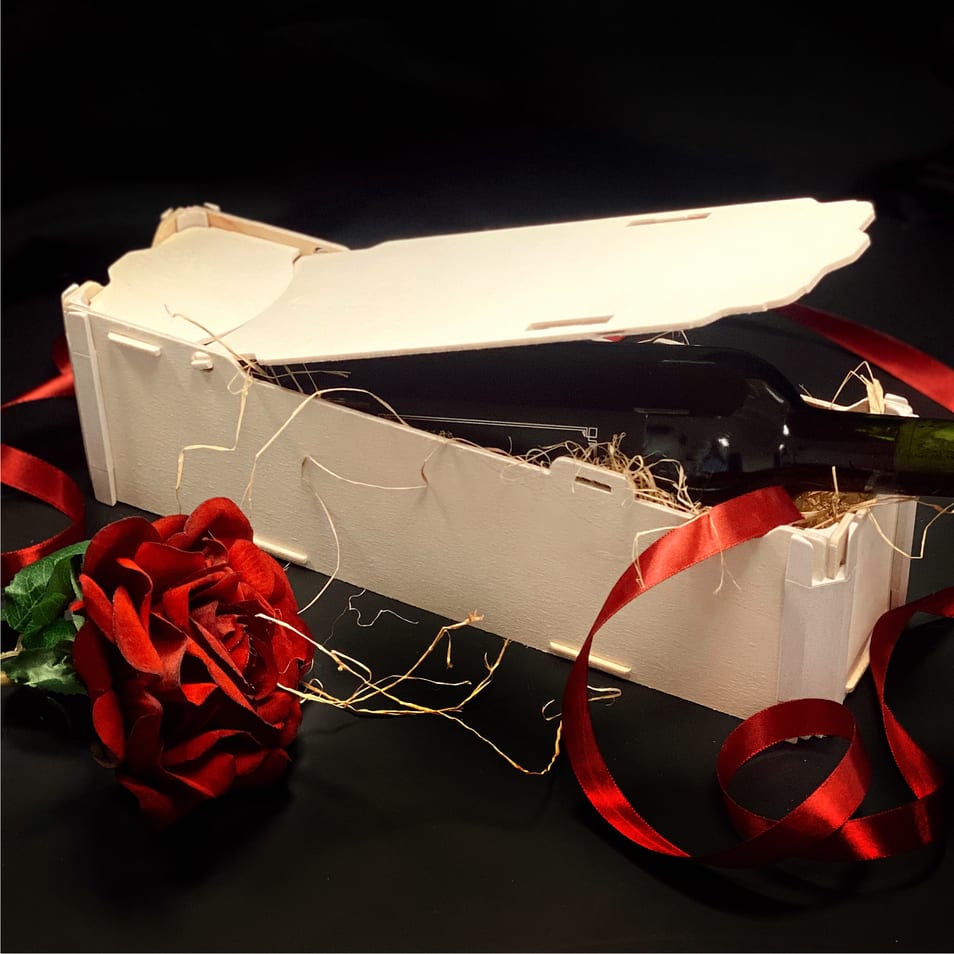 Wooden box for a bottle lying flat with the lid half open, a red rose and red ribbon on a black background