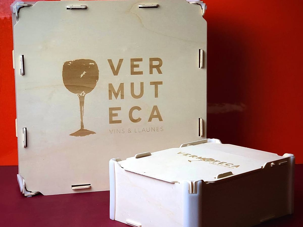 Wooden box with lid engraved with a vermouth bar’s logo (a glass and its name), next to a smaller box with the same logo
